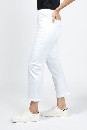 Holland Ave Denim Frayed Crop in white. Pull on pant with hidden elastic waist and faux fly. Smooth through the stomach and thigh, falls straight to the hem. 2 back curved patch pockets. Frayed hem. 26" inseam._34977857306824