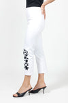 Holland Ave Embroidered Denim Crop in White with black floral embroidery on lower left leg. Hidden elastic waistband, faux fly pull on pant. 2 back rounded patch pockets. Snug through stomach and hip. Tapered to hem. 1/2" cuff. 25 1/2" inseam._t_34980855087304
