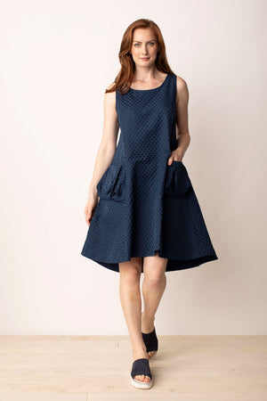 LIVy Habitat Sculpt Artist Dress in Navy. Textured jacquard dot parachute fabric. Sleeveless scoop neck dress with fitted bodice and flared skirt. High low hem. 2 large pouf pockets in front. Zip back. Relaxed fit._35020777259208
