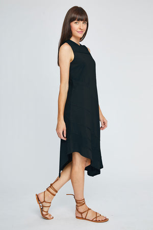 Neon Buddha Avalon Dress in Black. Sleeveless crew neck dress with front yoke in slub cotton. Asymmetric tiered, pieced hem with raw edges. Single front patch pocket. A line shape. Relaxed fit._35352682987720