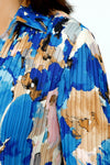 Cali Girls Watercolor Floral Pleated Blouse.  Shades of blue and beige large floral print.  Pointed collar with split v neck button down.  Long pleated sleeves.  Miniature vertical pleats around torso.  Relaxed fit._t_59451177861486