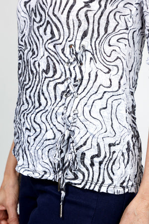 Top Ligne Squiggles Grommets Top in Black & White. Op art squiggle print in black on a white background. V neck 3/4 sleeve top with grommets and lace-up detail at left front hem. Relaxed fit._35010878275784
