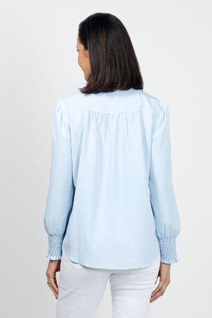 Beau Chemise Ruched Sleeve Popover in Sky. Banded crew neck with ruffle trim. Hidden 1/4 zipper front closure. Long sleeves with smocked cuff. Back yoke with soft gathers below. Shirt tail hem. Relaxed fit._35036162293960