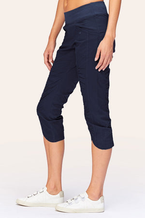 Wearables Iris Crop in Navy.  2 1/2" jersey waistband with poplin body.  2 deep front pockets with grommet detail.  Center seams and contour seams.  Ruched detail front and back.  Front tulip hem.  22" inseam._61270052962670