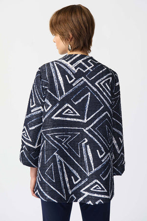Joseph Ribkoff Geometric Jacquard Jacket. White bold geometric print on a midnight blue background. Stand collar with asymmetric 1 button closure. 3/4 sleeve with wide cuff. High low hem. Relaxed fit._34829092913352