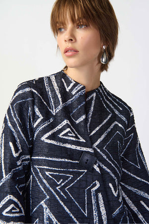 Joseph Ribkoff Geometric Jacquard Jacket. White bold geometric print on a midnight blue background. Stand collar with asymmetric 1 button closure. 3/4 sleeve with wide cuff. High low hem. Relaxed fit._34829092880584