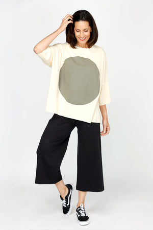 Planet ORB T in Butter with a large Green screen print circle in front. Crew neck with drop shoulder and 3/4 length sleeve. High low hem. Oversized fit. Pair with Spa Gaucho in Black_60432418308462
