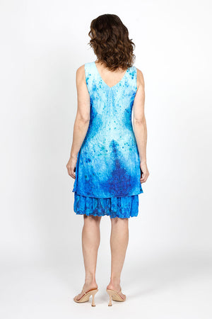 Top Ligne Watercolor Speckles Dress in Blue. Speckled watercolor print in shades of blue. Sleeveless v neck dress with 2 attached layers. Bottom layer has attached ruffle at hem. Top shorter layer. Relaxed fit._35408815685832