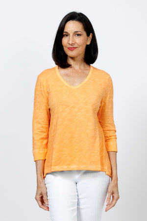 Elliott Lauren V Neck Seam Detail Tee in Tiger Lily, a light orange. V neck garment dyed 3/4 sleeve top. Wrapped contour seams from front to back. Asymmetric hem. Rib detail at neck hem and cuff. Relaxed fit._35201251279048