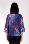 Frederique Ruffle Squares Jacket in Blue Multi. Abstract geometric print in bright colors on a royal blue base. Button front jacket with ruffle trim at neck and button placket. Adjustable wire collar. 3/4 sleeve with puffed cuff. Relaxed fit._t_34616135155912