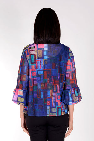 Frederique Ruffle Squares Jacket in Blue Multi. Abstract geometric print in bright colors on a royal blue base. Button front jacket with ruffle trim at neck and button placket. Adjustable wire collar. 3/4 sleeve with puffed cuff. Relaxed fit._34616135155912