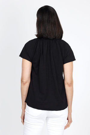 Mododoc Ruffle Henley Swing Tee in Black. Crew neck with open v placket. Raglan short sleeve. Ruffle at neck. Swing shape. Raw edges. Relaxed fit._35299706765512