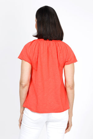 Mododoc Ruffle Henley Swing Tee in Fiery Tangerine. Crew neck with open v placket. Raglan short sleeve. Ruffle at neck. Swing shape. Raw edges. Relaxed fit._35299706699976
