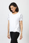 Mododoc Mixed Media Shirred Tee in White. Solid front with sketched black flower and vine pattern on sleeves and back.  Crew neck with short puffed sleeve.  Side seams wrap to front.  Raw edge at sleeve and hem.  High low hem. Relaxed fit._t_60036907860334
