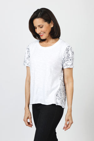 Mododoc Mixed Media Shirred Tee in White. Solid front with sketched black flower and vine pattern on sleeves and back.  Crew neck with short puffed sleeve.  Side seams wrap to front.  Raw edge at sleeve and hem.  High low hem. Relaxed fit._60036907860334