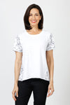 Mododoc Mixed Media Shirred Tee in White. Solid front with sketched black flower and vine pattern on sleeves and back.  Crew neck with short puffed sleeve.  Side seams wrap to front.  Raw edge at sleeve and hem.  High low hem. Relaxed fit._t_60036906582382