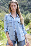 Billy T Flower Denim Shirt in light denim.  Button down shirt with embroidered multi colored flowers front and back.  2 front patch pockets with button flaps.  Long sleeve with button cuff.  Button roll tab on sleeves.  High low hem.  Side slits.  Relaxed fit._t_34229089435848