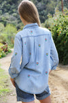Billy T Flower Denim Shirt in light denim. Button down shirt with embroidered multi colored flowers front and back. 2 front patch pockets with button flaps. Long sleeve with button cuff. Button roll tab on sleeves. High low hem. Side slits. Relaxed fit._t_34229089468616