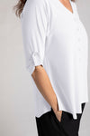 Sympli Convoy Henley in White. V neck with 5 button placket. 3/4 sleeve with button tab closure in satin crepe. Back yoke with inverted pleat below. Curved hem. Side slits. Relaxed fit._t_35065503154376
