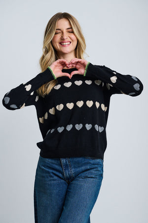 Lisa Todd Love Tracks Sweater in Black with 1 row each of white, beige and gray intarsia hearts.  Cotton/cashmere pullover crew neck sweater.  Long sleeves with dropped shoulders.  Intarsia hearts in front and sleeves.  Plain back.  Blanket stitch trim at cuffs. Rib trim at neck hem and cuff.  Classic fit._61429884485998