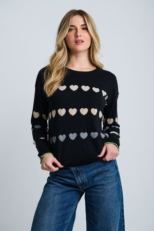 Lisa Todd Love Tracks Sweater in Black with 1 row each of white, beige and gray intarsia hearts.  Cotton/cashmere pullover crew neck sweater.  Long sleeves with dropped shoulders.  Intarsia hearts in front and sleeves.  Plain back.  Blanket stitch trim at cuffs. Rib trim at neck hem and cuff.  Classic fit._61429884518766