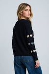Lisa Todd Love Tracks Sweater in Black with 1 row each of white, beige and gray intarsia hearts.  Cotton/cashmere pullover crew neck sweater.  Long sleeves with dropped shoulders.  Intarsia hearts in front and sleeves.  Plain back.  Blanket stitch trim at cuffs. Rib trim at neck hem and cuff.  Classic fit._t_61429886189934