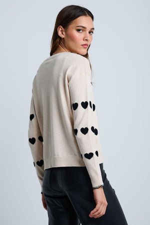 Lisa Todd Love Tracks Sweater in Sheepskin with black intarsia hearts.  Cotton/cashmere pullover crew neck sweater.  Long sleeves with dropped shoulders.  Intarsia hearts in front and sleeves.  Plain back.  Blanket stitch trim at cuffs. Rib trim at neck hem and cuff.  Classic fit._61429884584302