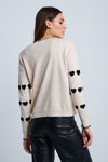 Lisa Todd Love Tracks Sweater in Sheepskin with black intarsia hearts.  Cotton/cashmere pullover crew neck sweater.  Long sleeves with dropped shoulders.  Intarsia hearts in front and sleeves.  Plain back.  Blanket stitch trim at cuffs. Rib trim at neck hem and cuff.  Classic fit._t_61429884617070