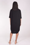 Perlavera Dina Dress in Black. Below the knee popover dress with pointed spread collar, hidden button placket and short cuffed sleeves. Curved high low hem. In seam pockets. One size fits most._t_34324036059336
