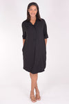 Perlavera Dina Dress in Black. Below the knee popover dress with pointed spread collar, hidden button placket and short cuffed sleeves. Curved high low hem. In seam pockets. One size fits most._t_34324035928264