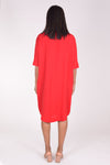 Perlavera Dina Dress in Red. Below the knee popover dress with pointed spread collar, hidden button placket and short cuffed sleeves. Curved high low hem. In seam pockets. One size fits most._t_34324035993800