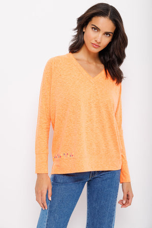Lisa Todd Beach Tee in Tangerine. V neck tee with raglan long sleeve. Banded cuff. Banded hem with side slits. Multi colored hand stitch detail in front. Relaxed fit._35222810788040