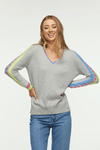 Zaket & Plover Jacquard Sleeve Sweater in Marled Gray. V neck sweater with long sleeves. Color block stripe and block print on center sleeve. Striped trim at neck and cuff. Ribbed at neck, cuff and hem. Side slits. Relaxed fit._t_34536815984840