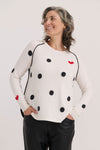 Zaket & Plover Spot the Love Sweater in White.  Black intarsia dot print on front and sleeves with red hearts.  Crew neck long raglan sleeve sweater with black piping at armhole seams.  Solid black back.  Curved hem.  Ribbed trim at neck and cuff.  Relaxed fit._t_61045824258414
