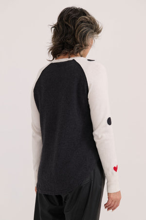 Zaket & Plover Spot the Love Sweater in White.  Black intarsia dot print on front and sleeves with red hearts.  Crew neck long raglan sleeve sweater with black piping at armhole seams.  Solid black back.  Curved hem.  Ribbed trim at neck and cuff.  Relaxed fit._61045824291182