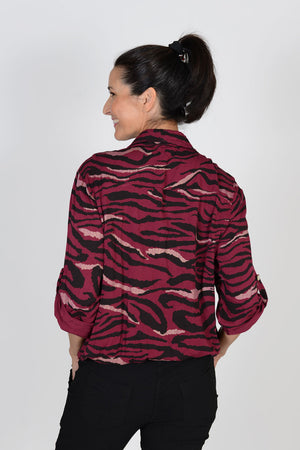 Cali Girls Animal Print Top in Berry/Black. Zebra print in black and gold metallic on berry red background. Pointed collar button down shirt with rope drawstring at hem. Bracelet length sleeve with button roll tab. Relaxed fit._33425961025736