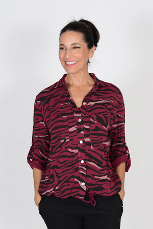Cali Girls Animal Print Top in Berry/Black.  Zebra print in black and gold metallic on berry red background.  Pointed collar button down shirt with rope drawstring at hem.  Bracelet length sleeve with button roll tab.  Relaxed fit._33425960992968