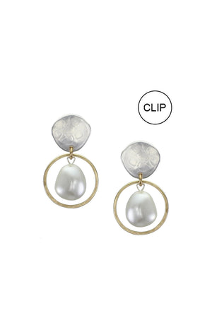 Stylish and modern dangle earrings each featuring a luminous white pearl framed by a golden brass ring hanging from a hammer textured organic shaped silver stud with a  standard hypoallergenic earring clip backing._33891613278408