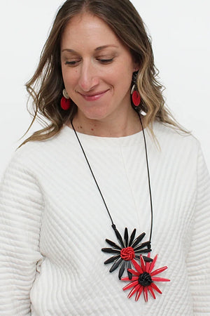 The Floral Statement Necklace is a wearable piece of art! This sculptural and unique necklace features two handcrafted wooden flowers in black and red with clusters of tiny beads in the centers in corresponding colors adding dimension to these artful pendants. _33973397455048