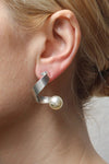 The Curly Pearl Earrings are a modern and sculptural pair of earrings each featuring silver curled strip with a suspended cream colored Austrian crystal pearl at the ends on a standard earring post with push backs._t_32819761676488