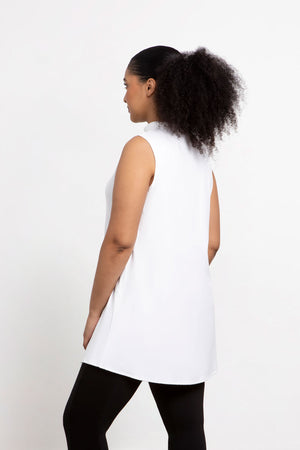 Sympli Sleeveless Mock Neck Slit Tunic in White. Mock neck long top with asymmetric front hem. Off side wrapped seam with slit. Relaxed fit. Tunic length._34038761324744